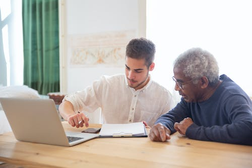 a male nurse helping an old man with paper work