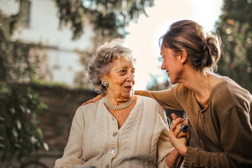 a young lady speaking to an old woman